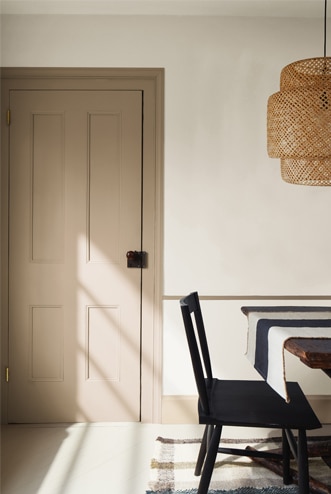 Salle à manger neutre avec porte havane, table en bois foncé et chaise noire.